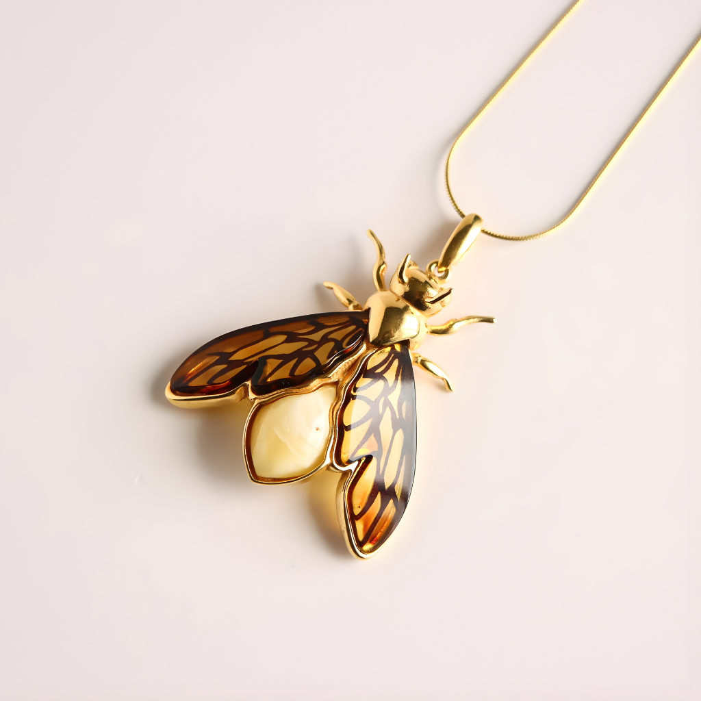 Gold bumble bee pendant amber necklace on a light background