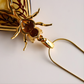 Gold bumble bee shaped pendant amber necklace on a chain against a light background