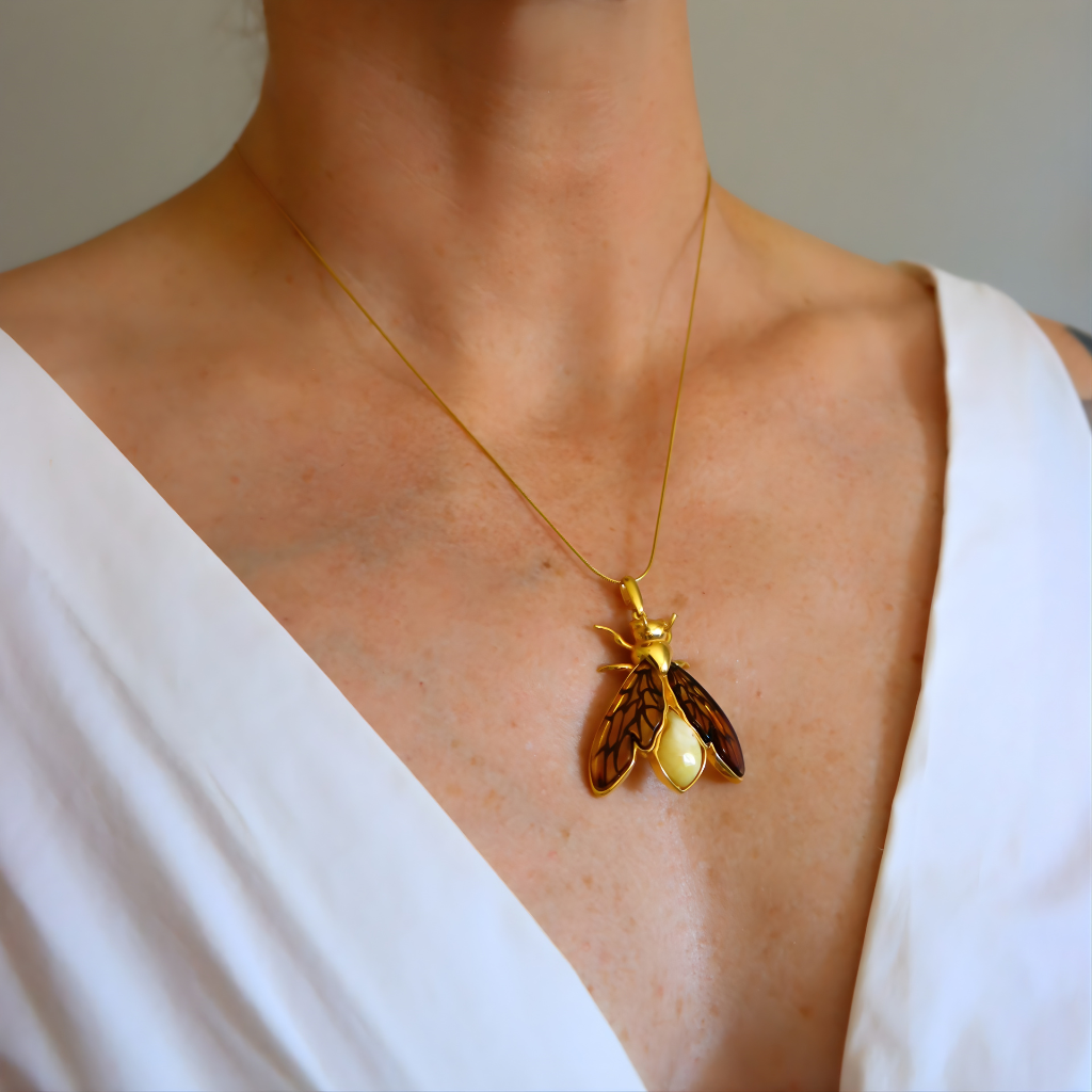 Gold amber necklace with a unique pendant worn by a person in a white top.