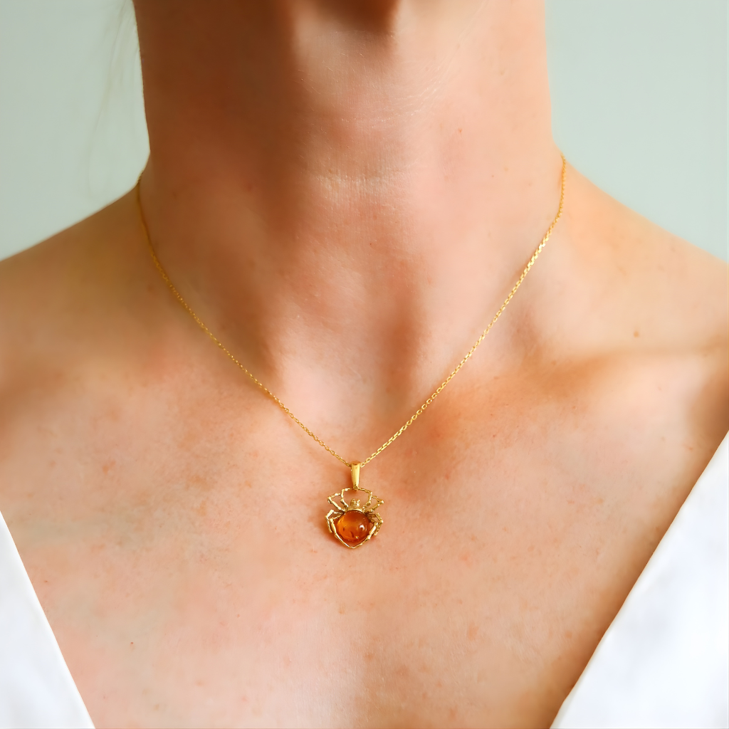 Gold amber necklace with a spider-shaped pendant worn by a person
