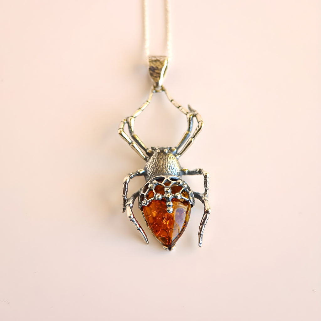 Spider-shaped pendant amber necklace with amber stone on a light pink background