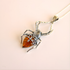 Spider-shaped pendant amber necklace with amber stone on a beige background