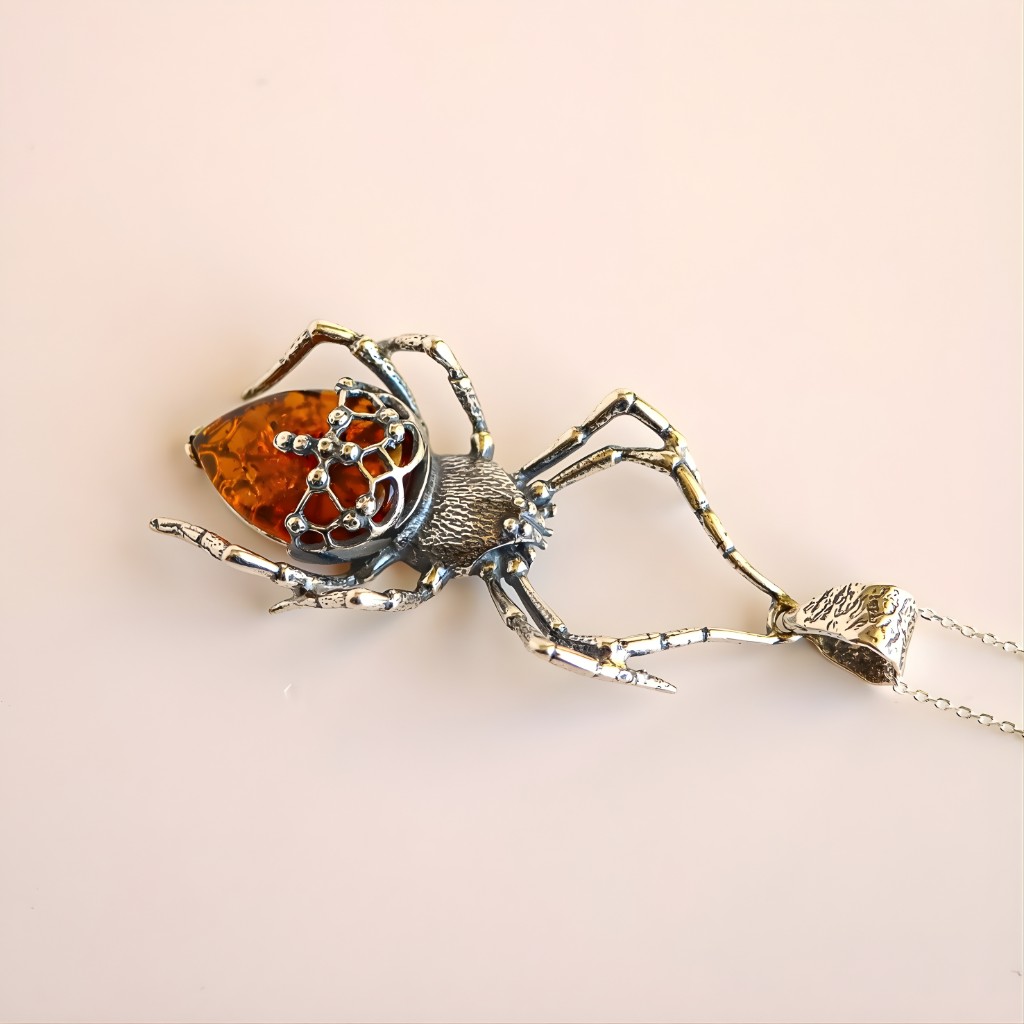 Spider-shaped pendant amber necklace with amber center on a beige background