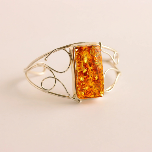 silver cuff bracelet with a rectangular amber stone on a beige background