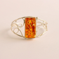 cuff bracelet with a rectangular amber stone on a beige background