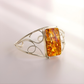 Silver cuff bracelet with a rectangular amber stone on a light background