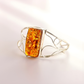 Silver cuff bracelet with a rectangular amber stone on a light background