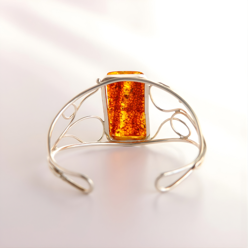 silver cuff bracelet with amber-colored stone on a light background