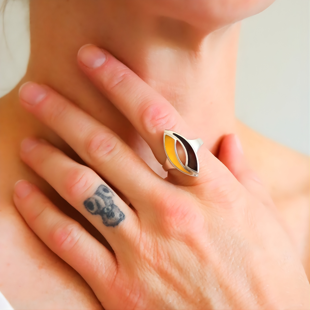 Close-up of a hand wearing a unique amber ring with a cat-eye design.