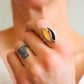 Close-up of a hand wearing a silver amber ring with a yellow and black design.