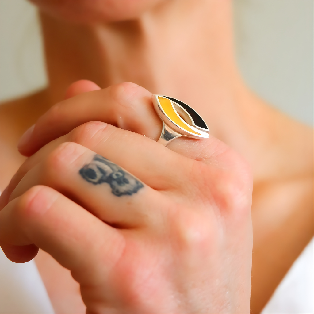 Close-up of a hand wearing a colorful amber ring with a blurred background