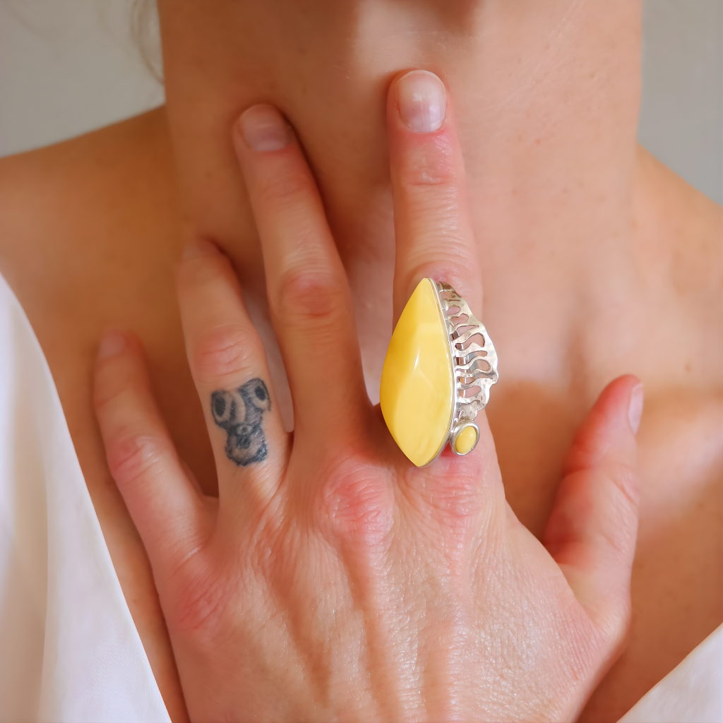 Close-up of a hand wearing a Butterscotch amber ring with a silver band.