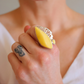 Close-up of a hand wearing a butterscotch amber ring with a silver band.