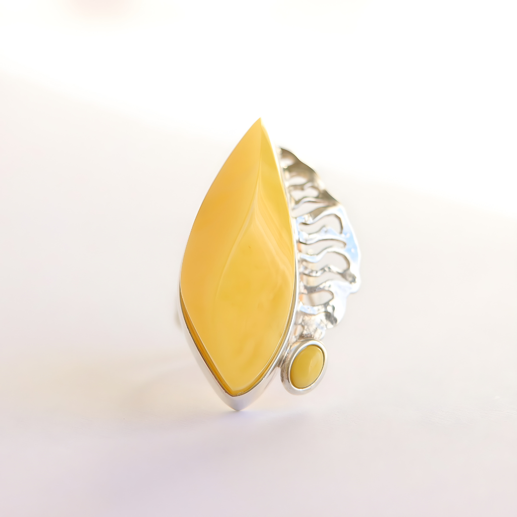butterscotch amber Ring with yellow teardrop-shaped stone and silver band on a light background