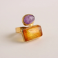 Gold amber ring with a purple gemstone on a light beige background