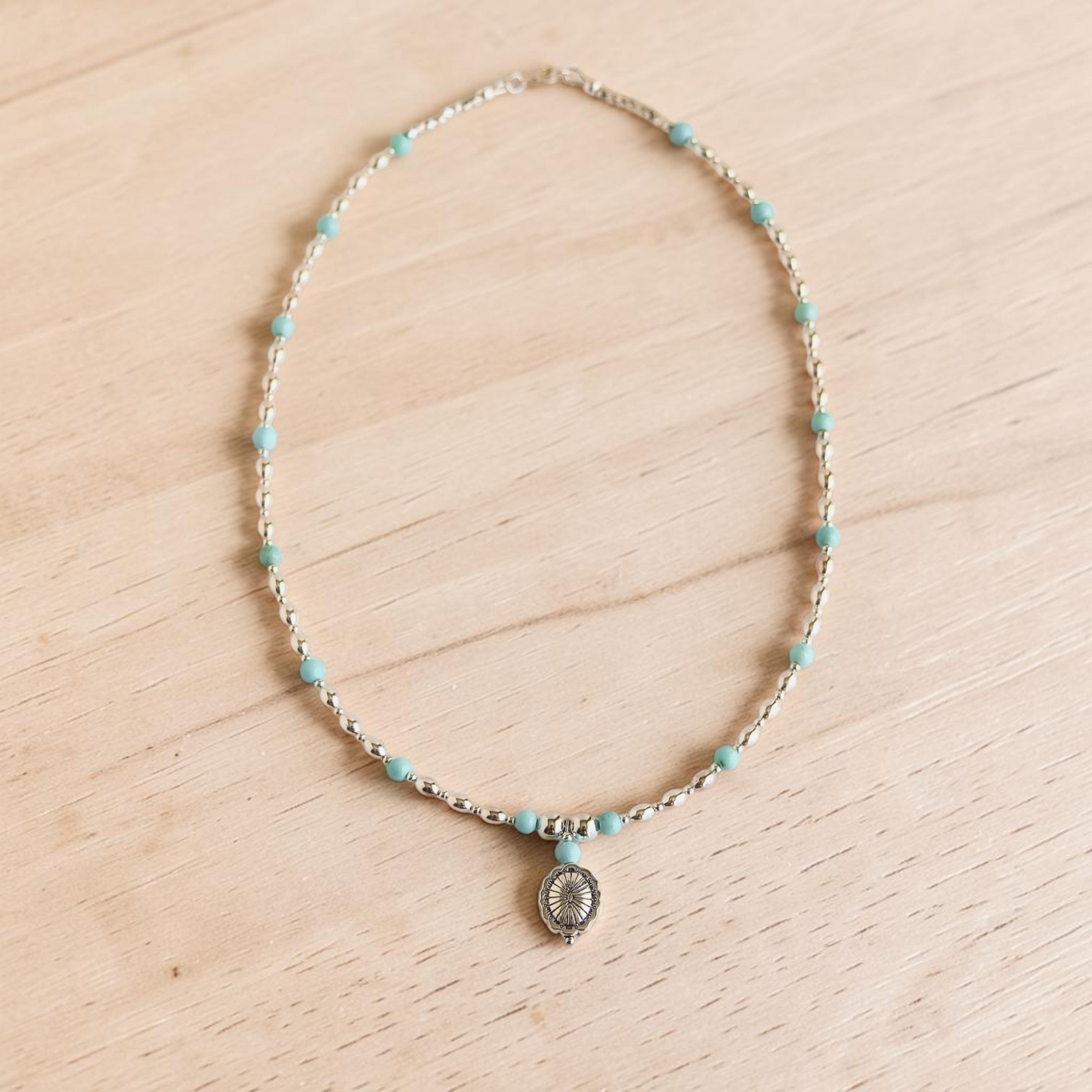 Turquoise Necklace on white wood background with silver pendant