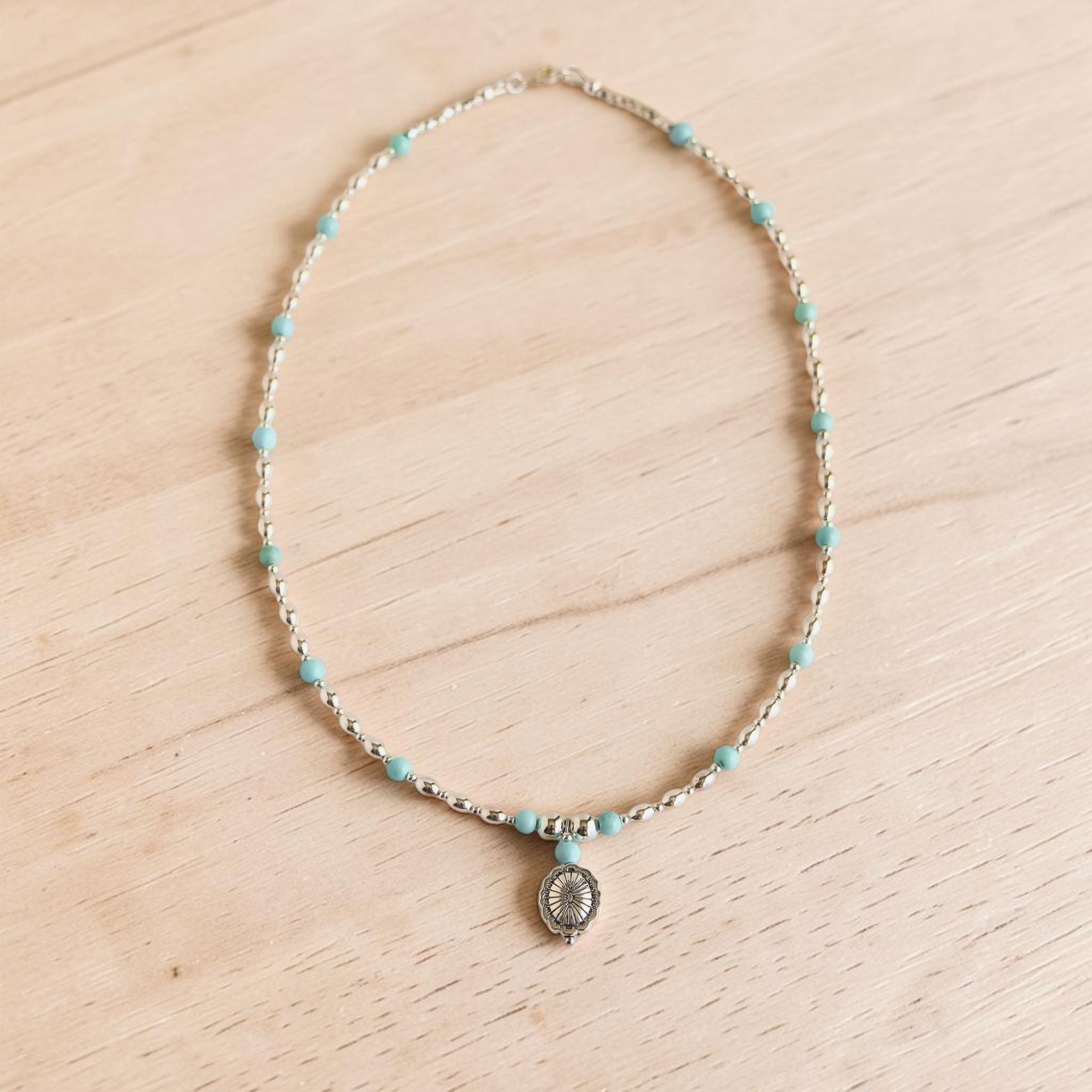 Turquoise Necklace on white wood background with silver pendant