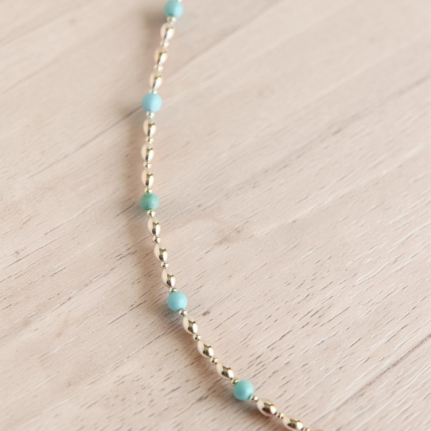 Turquoise necklace with silver beads on white gray textured background