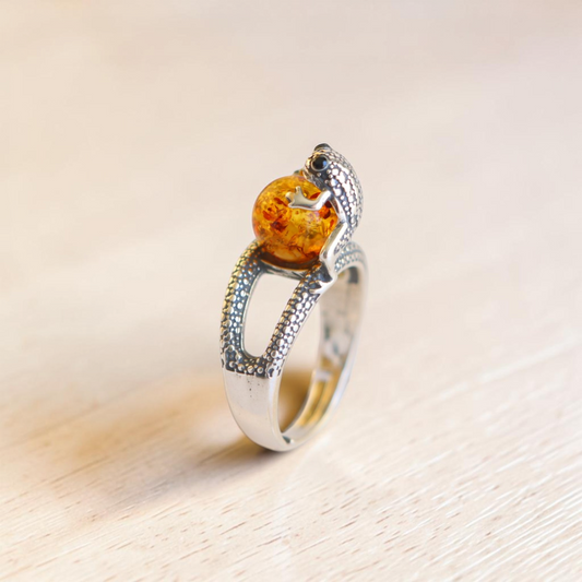 Sterling silver frog ring with round Baltic amber cabochon and adjustable textured band.