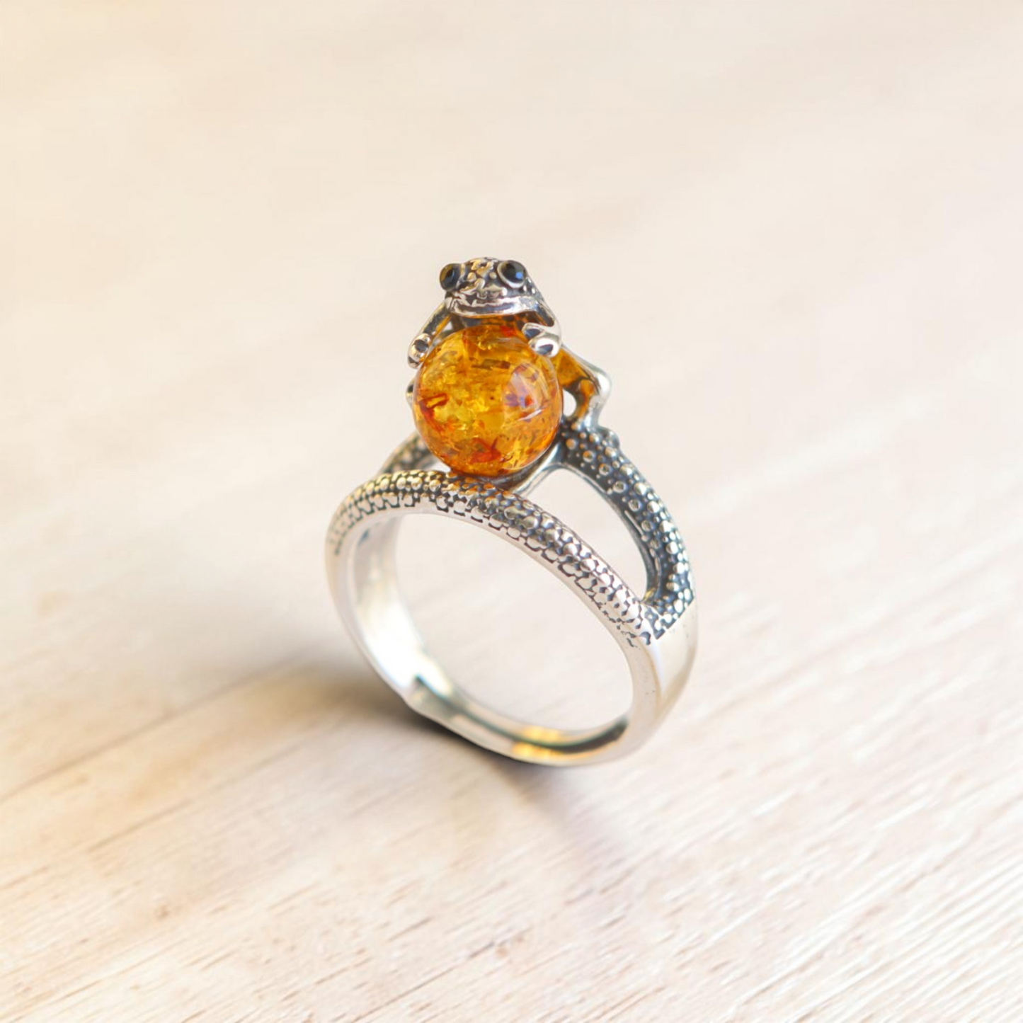 Sterling silver frog ring with round Baltic amber cabochon and adjustable textured band.