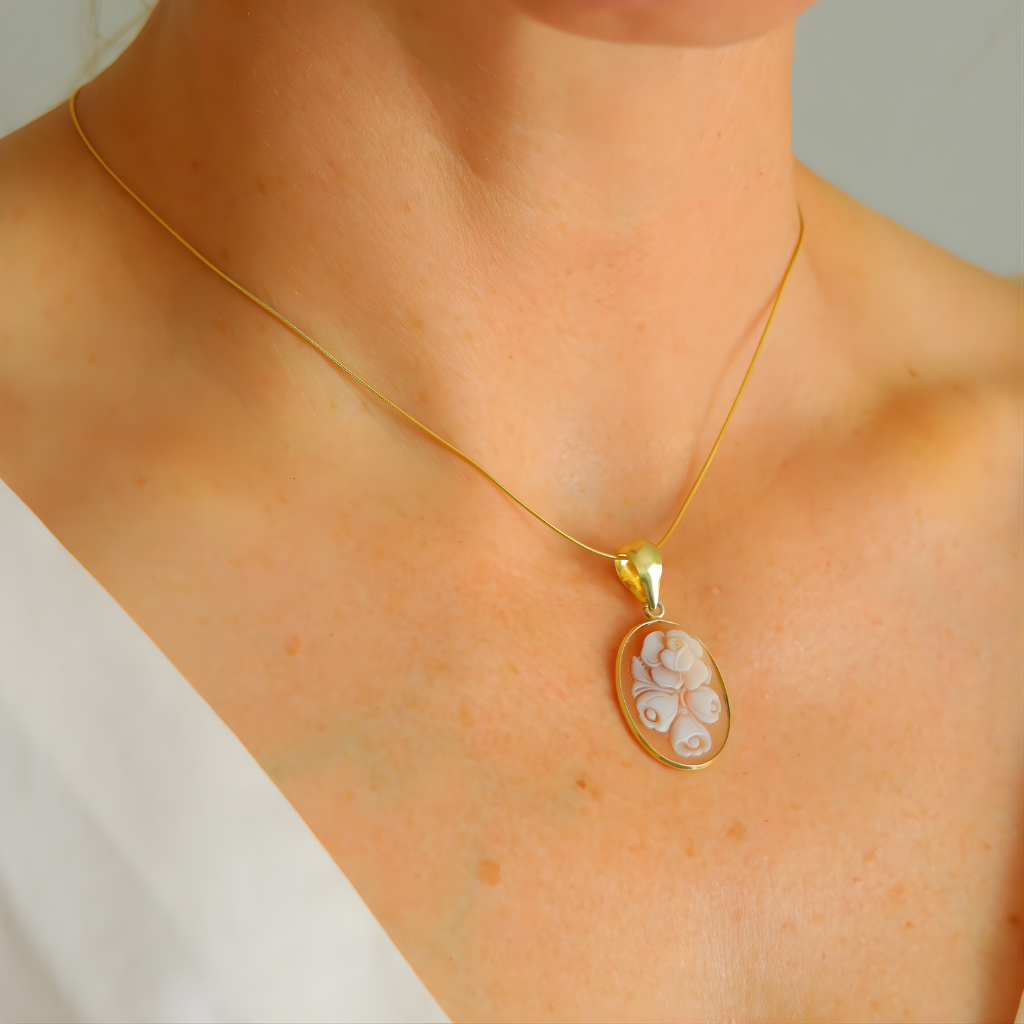 Gold flower necklace on a person wearing a white top.