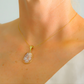 Gold flower necklace on a person's neck against a neutral background