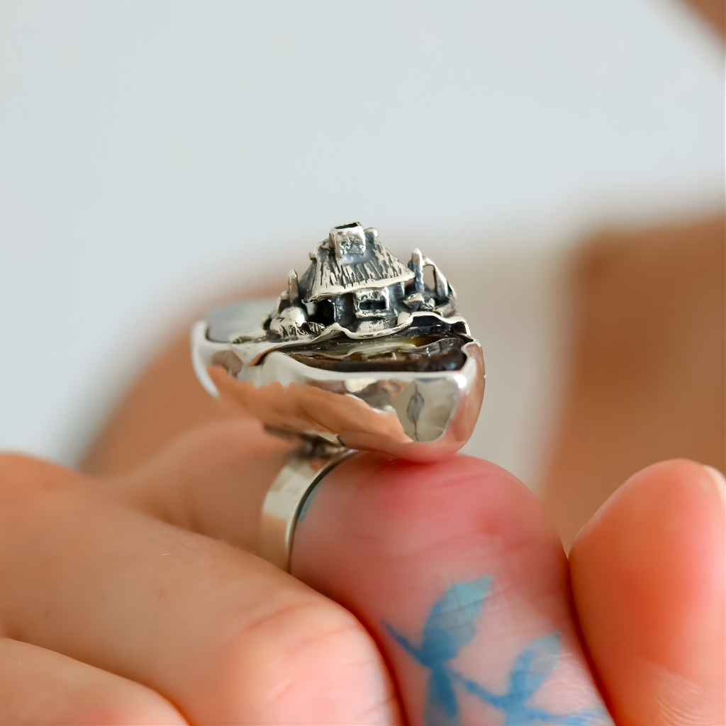 Silver amber ring on a finger with a blurred background