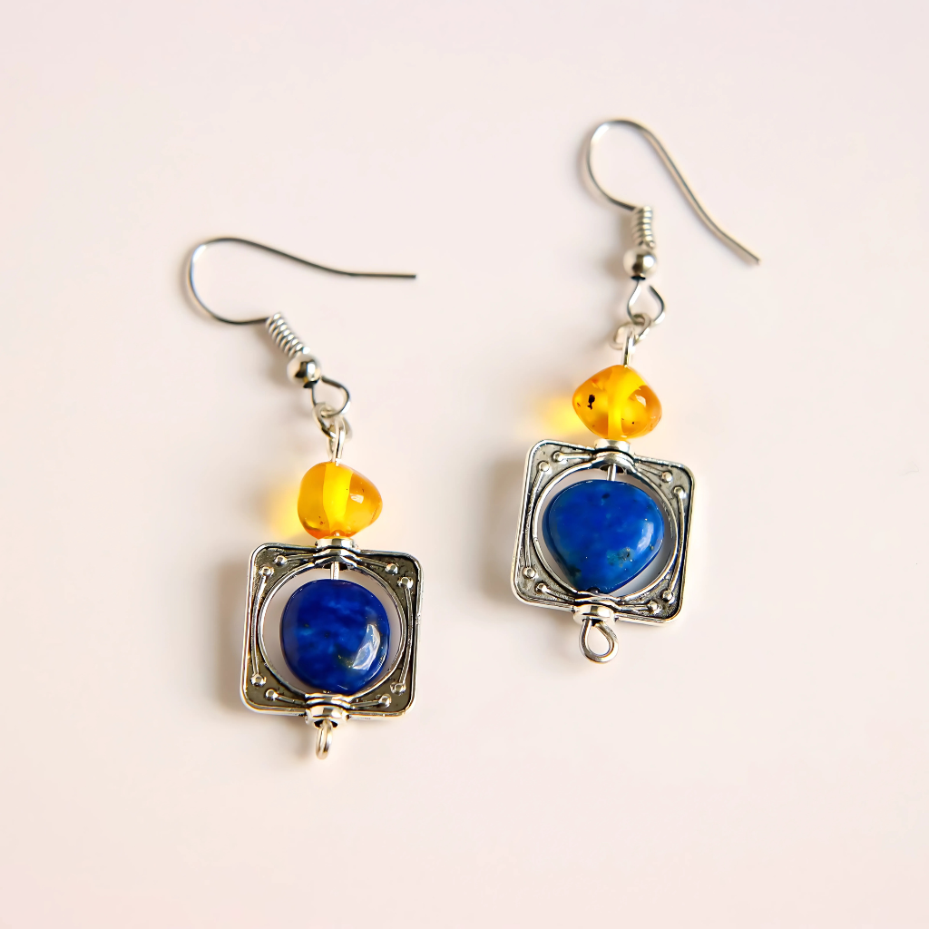 Pair of lapis earrings with blue and orange beads on a light pink background