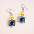 Pair of lapis earrings with blue and orange beads on a light pink background