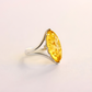 Silver amber ring with a large yellow gemstone on a light background