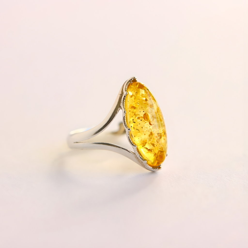Silver amber ring with a large yellow gemstone on a light background