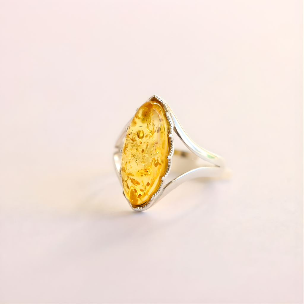 Amber Ring with a yellow stone and silver band on a light pink background