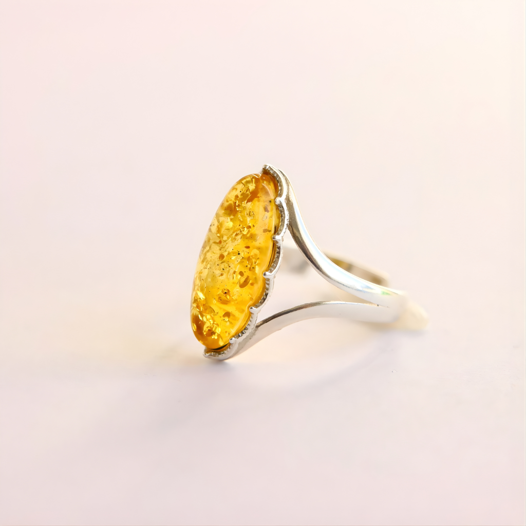 Silver amber ring with a large yellow gemstone on a light pink background
