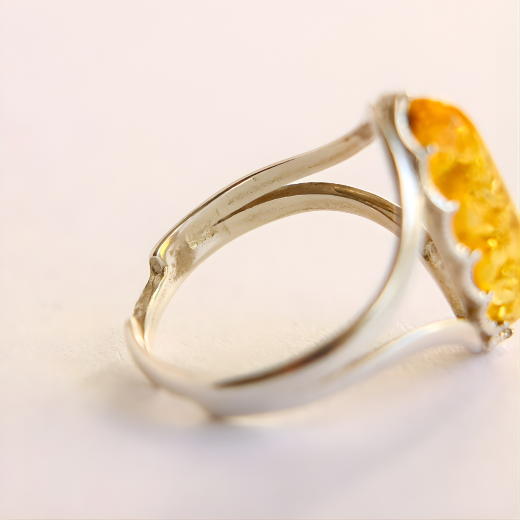 Silver amber ring with a yellow gemstone on a light background