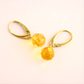 Gold amber earrings with yellow gemstones on a light background