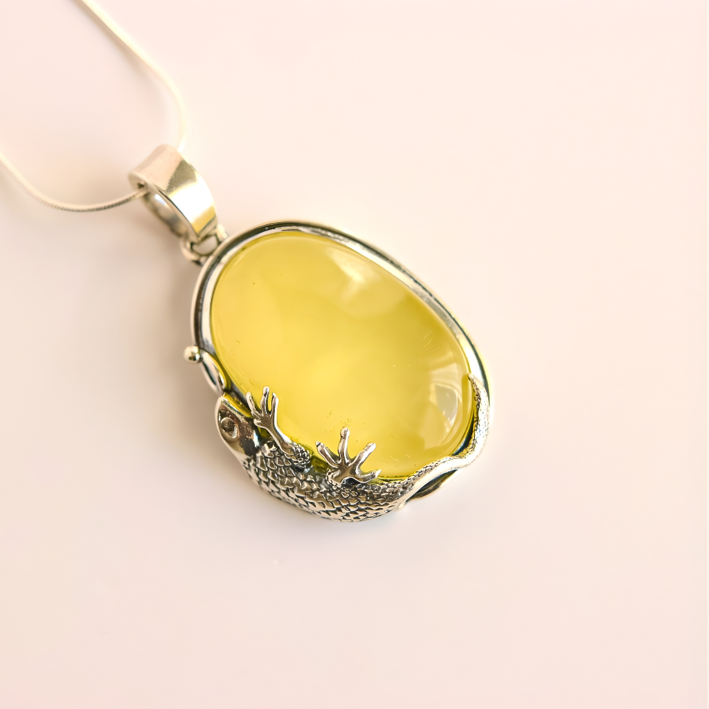 Yellow amber necklace with silver gecko design on a beige background
