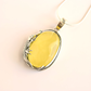 Yellow amber necklace with silver frame on a light pink background