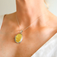 amber Necklace with a yellow pendant on a person wearing a white top.