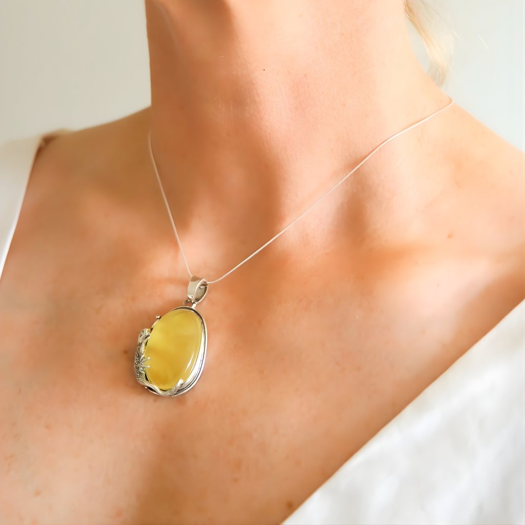 amber Necklace with a yellow pendant on a person wearing a white top.