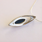 amber necklace with Silver pendant with black center on a light beige background