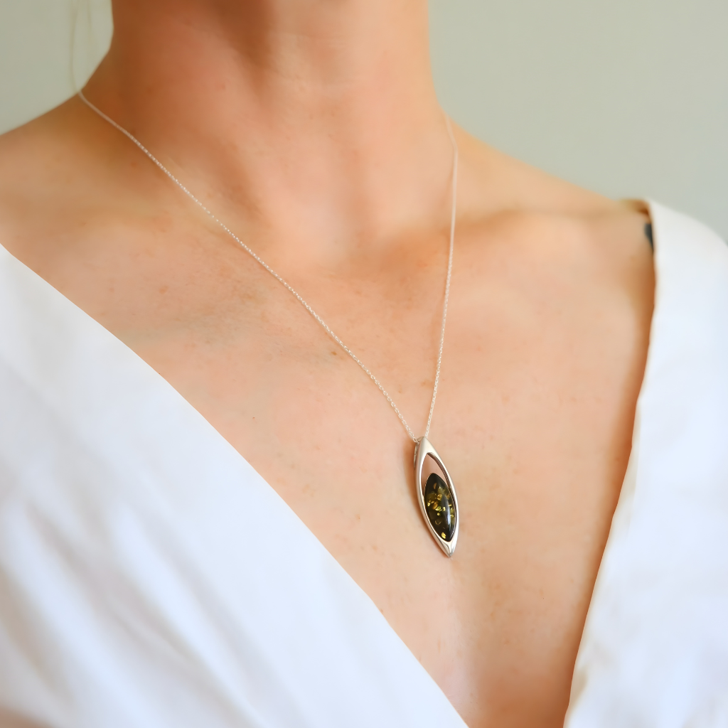 amber Necklace with a pendant worn by a person in a white top against a neutral background