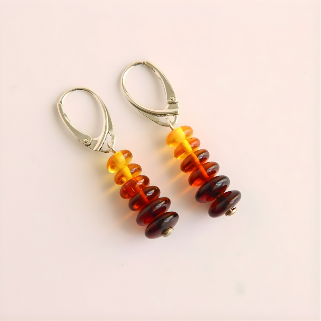 Pair of amber earrings with colorful beads on a light pink background
