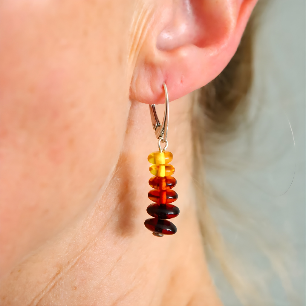 Amber beaded earrings worn on an ear with a blurred background