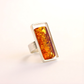 Silver amber ring with a rectangular amber stone on a white background