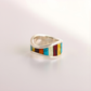 Silver amber ring with colorful inlay on a light gray background