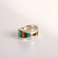 Silver amber ring with colorful inlay on a light gray background