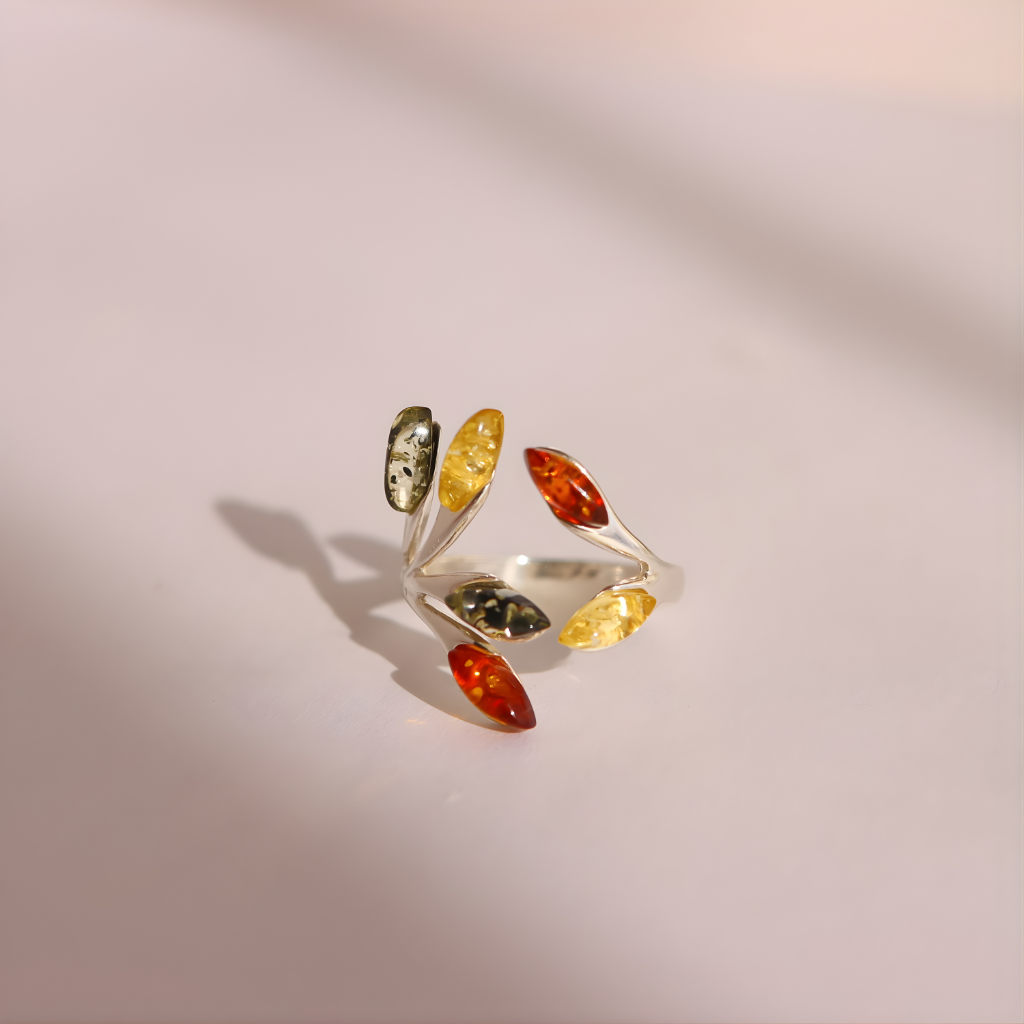 Silver amber ring with colorful gemstones on a light pink background