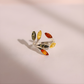 Silver amber ring with multicolored gemstones on a light pink background
