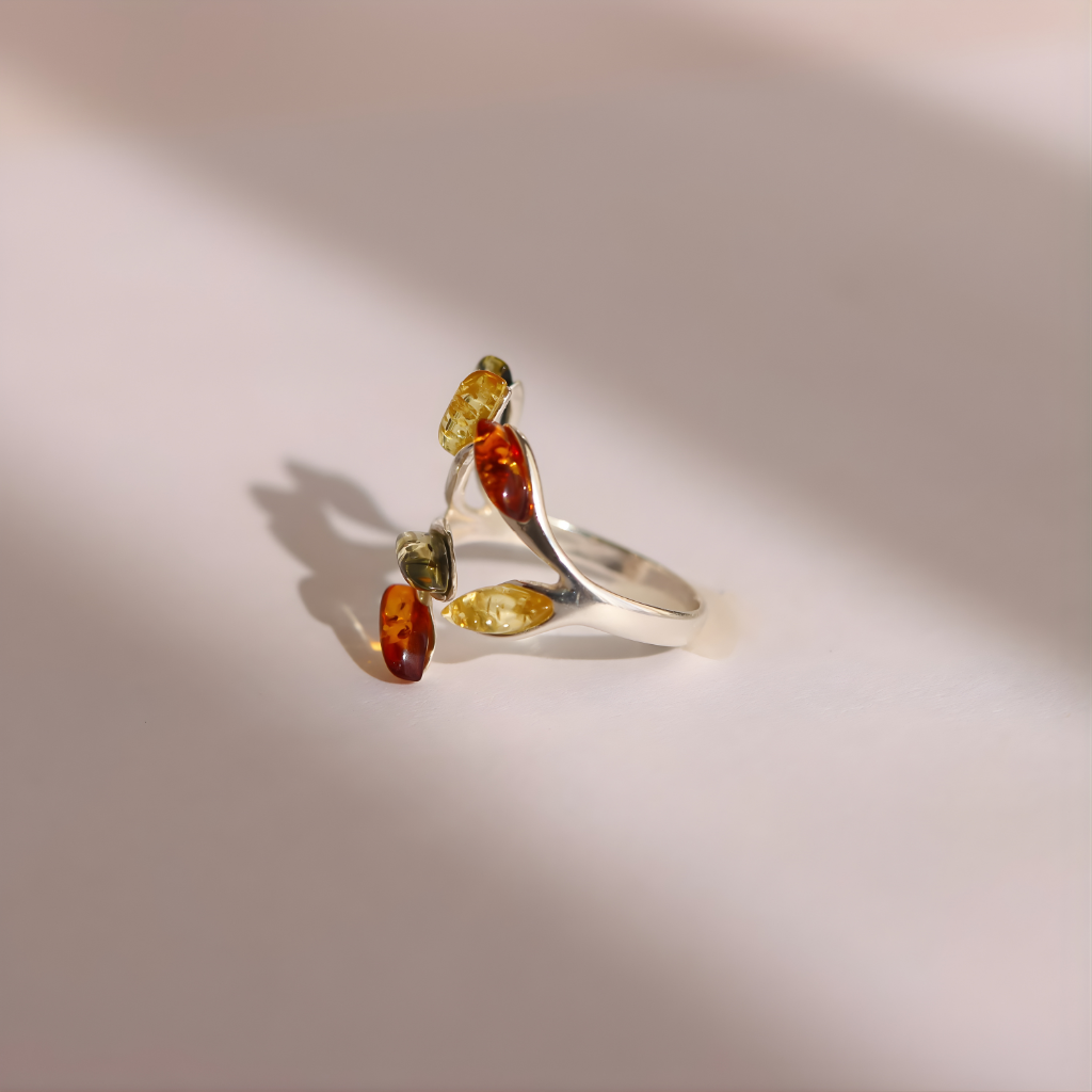 Silver amber ring with multicolored gemstones on a light background