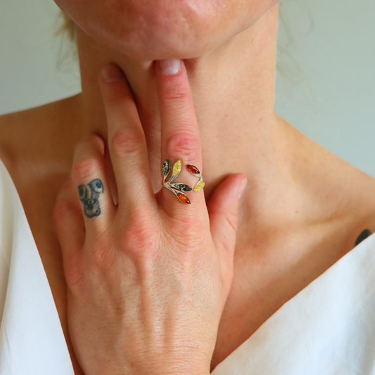 Close-up of a hand wearing a colorful amber ring with a neutral background